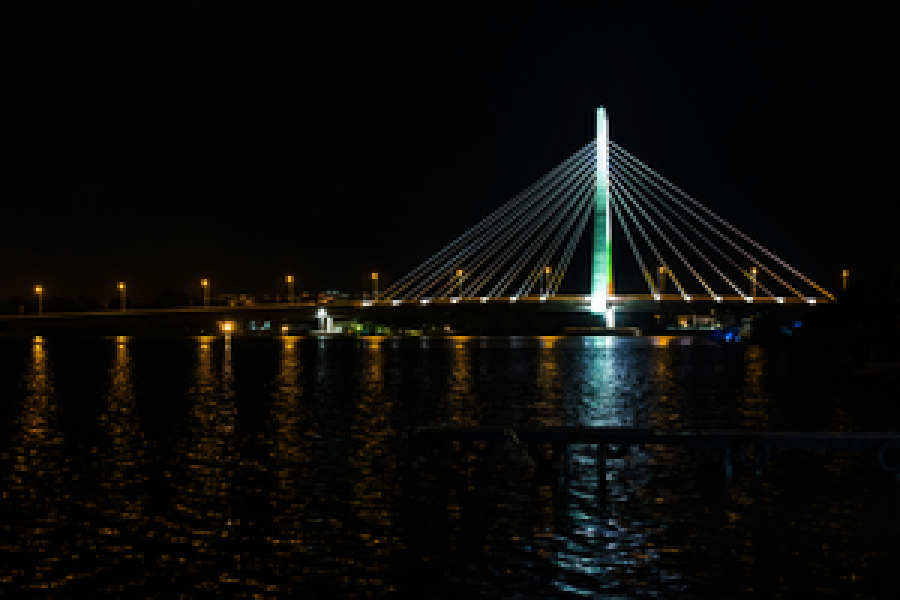 Lagos at night: a lit cable-stayed bridge reflected in the dark water of the lagoon.